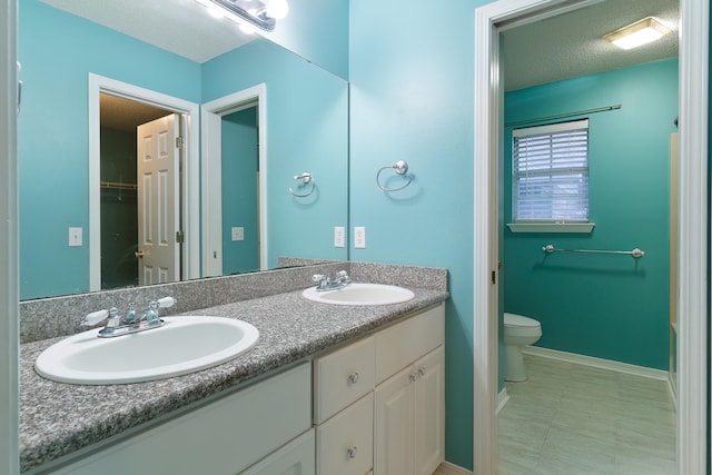 bathroom with a textured ceiling, vanity, and toilet