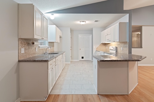 kitchen with kitchen peninsula, light wood-type flooring, sink, white range with electric cooktop, and lofted ceiling