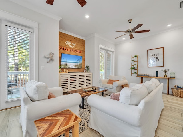 living room with ceiling fan, wood walls, and light wood-type flooring