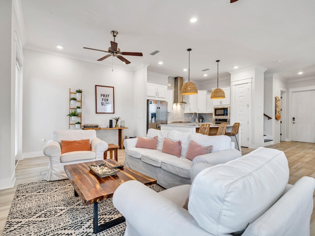 living room featuring ceiling fan, crown molding, and light hardwood / wood-style flooring