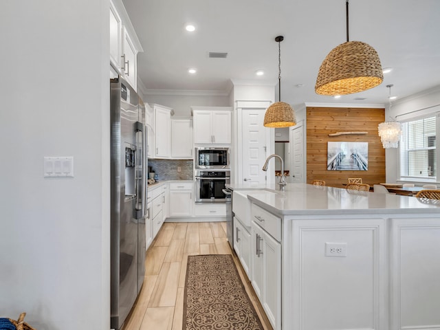 kitchen with sink, pendant lighting, a center island with sink, white cabinets, and appliances with stainless steel finishes