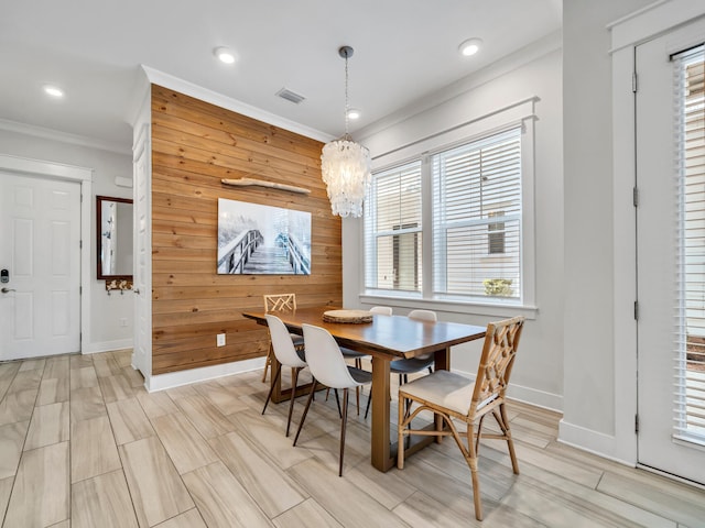 dining area featuring crown molding, wooden walls, and a chandelier