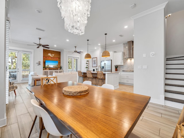 dining space with ceiling fan with notable chandelier, crown molding, and a healthy amount of sunlight