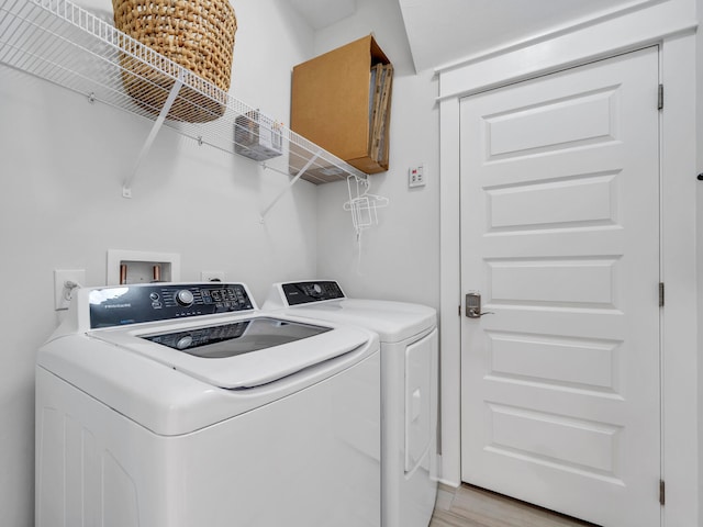 laundry room featuring washing machine and dryer and light hardwood / wood-style flooring