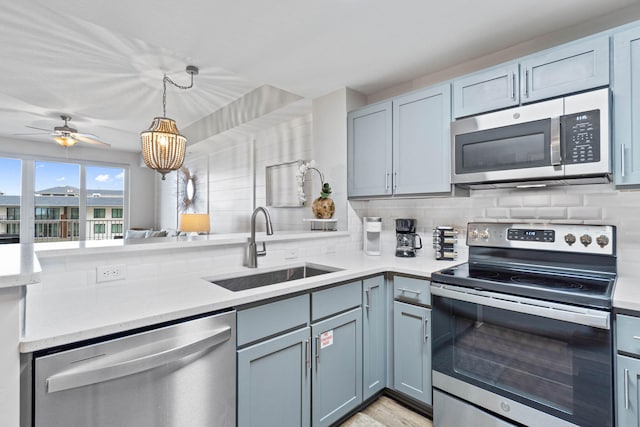 kitchen with pendant lighting, decorative backsplash, sink, and stainless steel appliances