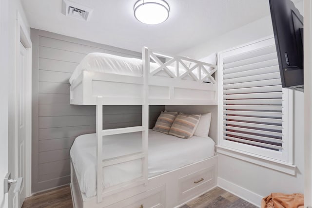 bedroom featuring wood walls and dark hardwood / wood-style flooring