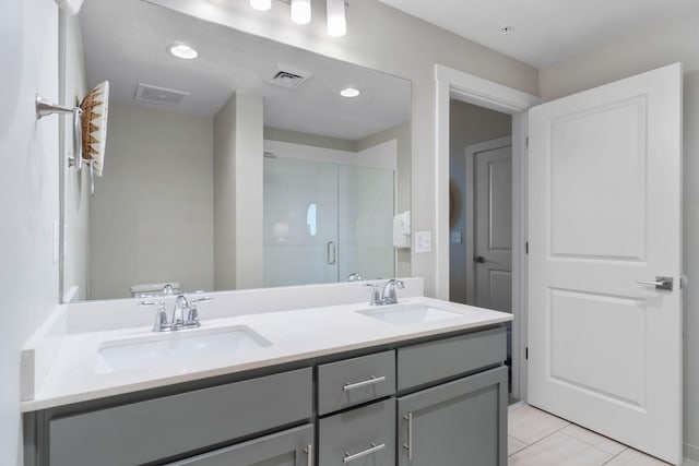 bathroom featuring toilet, a shower with door, vanity, and tile patterned flooring