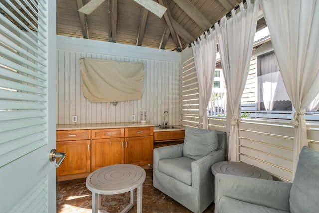 sitting room with lofted ceiling with beams, wood walls, and sink