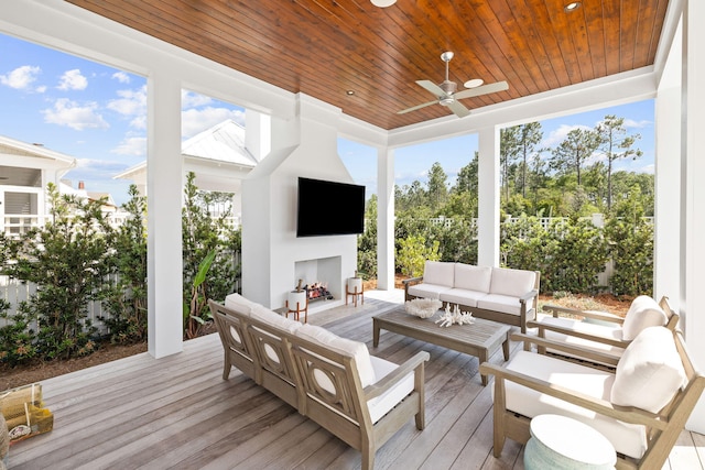 sunroom with exterior fireplace, wood ceiling, and ceiling fan