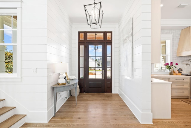 foyer featuring a chandelier, light hardwood / wood-style flooring, and a healthy amount of sunlight