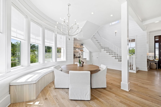 dining space featuring lofted ceiling, an inviting chandelier, light hardwood / wood-style flooring, and wooden walls