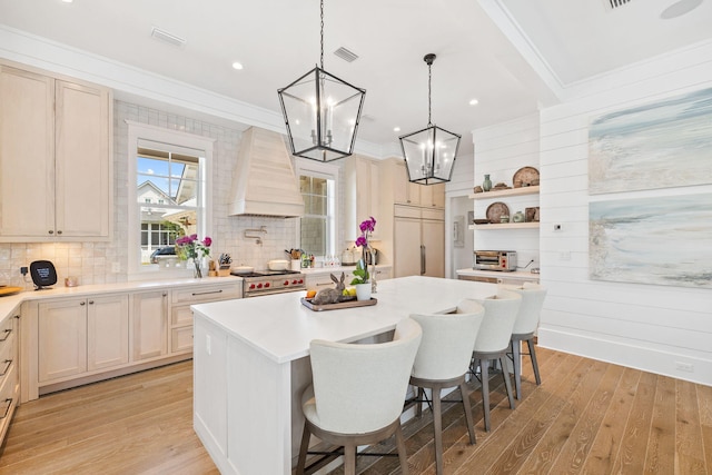 kitchen with a breakfast bar area, high quality appliances, a kitchen island, and light hardwood / wood-style floors