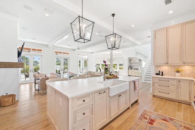 kitchen featuring beam ceiling, french doors, a center island, pendant lighting, and light wood-type flooring