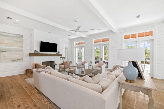 living room with french doors, beamed ceiling, light hardwood / wood-style floors, and plenty of natural light