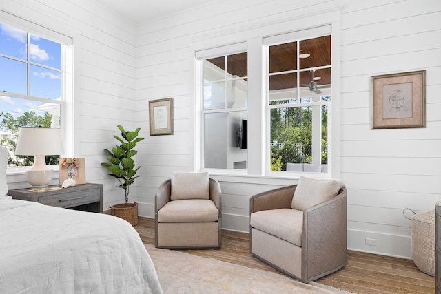 bedroom featuring multiple windows, wood walls, and light wood-type flooring