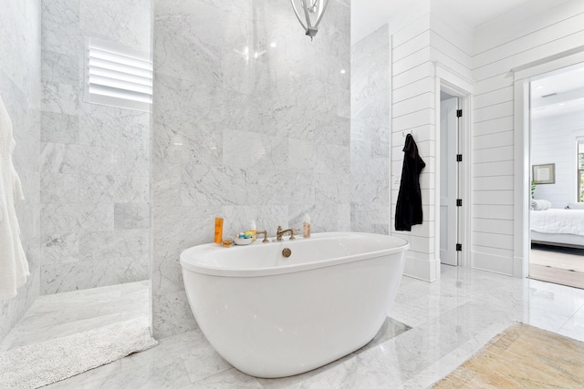 bathroom with a tub to relax in, a healthy amount of sunlight, and tile walls