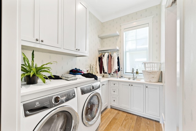 laundry room with sink, cabinets, independent washer and dryer, light wood-type flooring, and ornamental molding