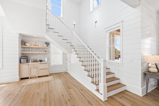 stairway with wood walls, a towering ceiling, and hardwood / wood-style flooring