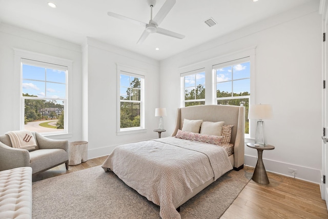 bedroom with light hardwood / wood-style flooring, ceiling fan, multiple windows, and crown molding