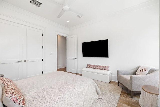 bedroom with light wood-type flooring, a closet, ceiling fan, and crown molding