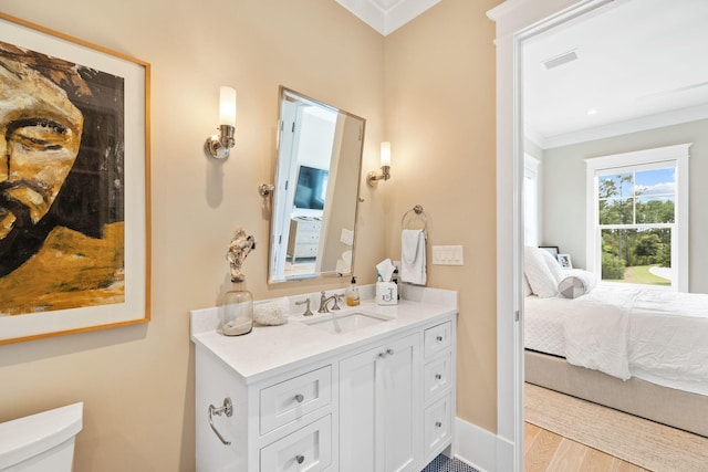 bathroom featuring vanity, hardwood / wood-style floors, ornamental molding, and toilet