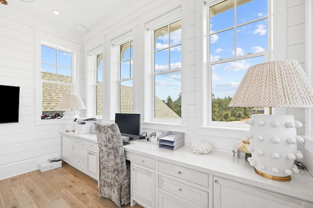 home office with crown molding, a wealth of natural light, built in desk, and light hardwood / wood-style floors