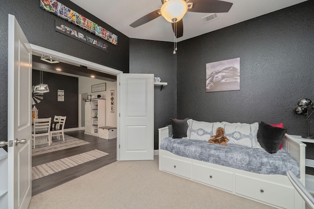 bedroom featuring a barn door, ceiling fan, and wood-type flooring