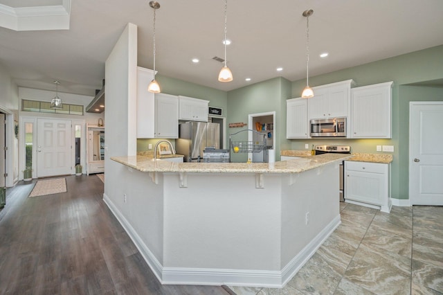 kitchen with kitchen peninsula, white cabinetry, stainless steel appliances, and a breakfast bar area