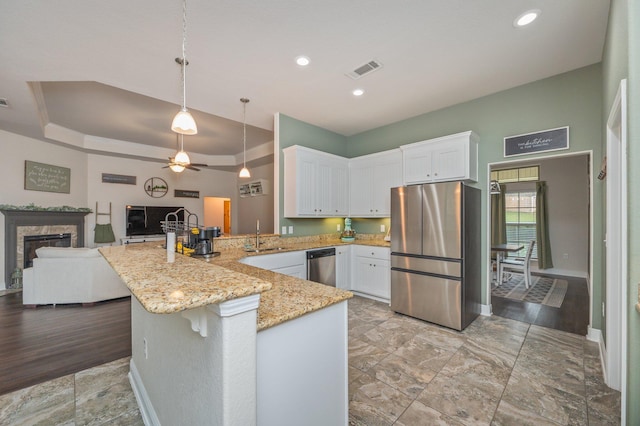 kitchen with white cabinets, light wood-type flooring, stainless steel appliances, and a premium fireplace