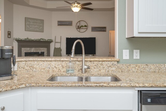 kitchen with white cabinets, light stone countertops, ornamental molding, and sink