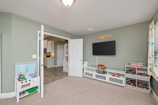 rec room featuring a textured ceiling and light carpet