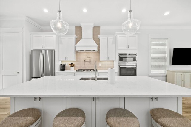 kitchen with a large island, pendant lighting, custom range hood, and stainless steel appliances