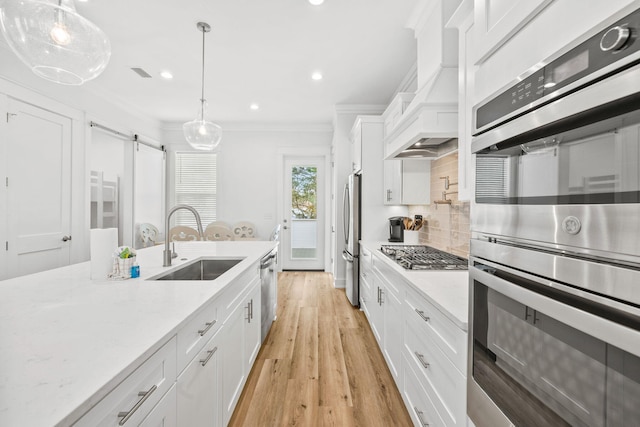 kitchen with stainless steel appliances, pendant lighting, sink, tasteful backsplash, and white cabinetry