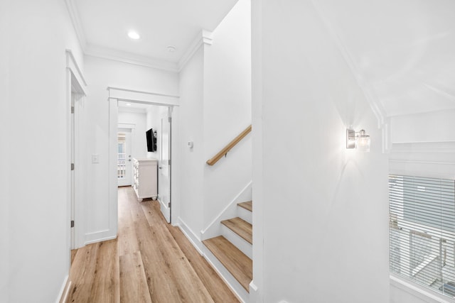 corridor with light hardwood / wood-style flooring and ornamental molding