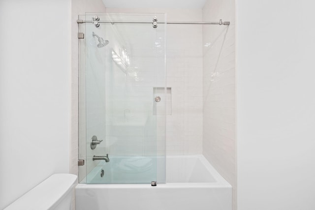 bathroom with toilet and bath / shower combo with glass door