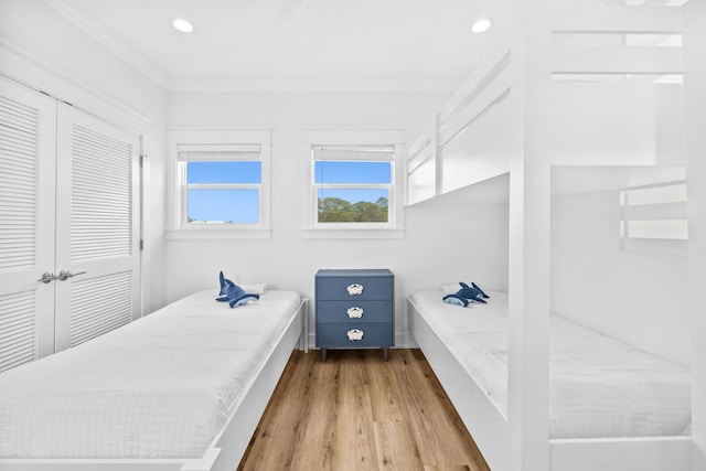 bedroom featuring a closet, light wood-type flooring, and crown molding