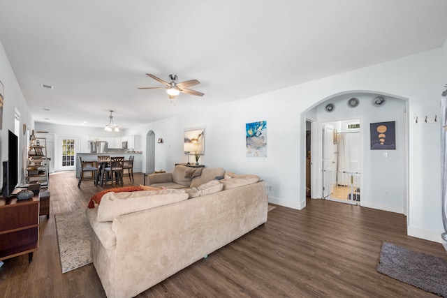 living room with baseboards, arched walkways, ceiling fan, and dark wood-style flooring