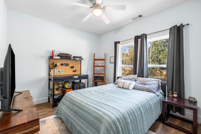 bedroom with dark wood-style floors, a ceiling fan, visible vents, and baseboards