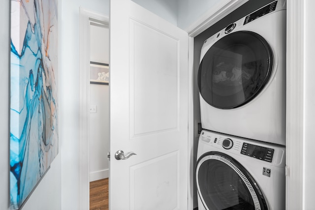 clothes washing area with stacked washing maching and dryer and hardwood / wood-style flooring