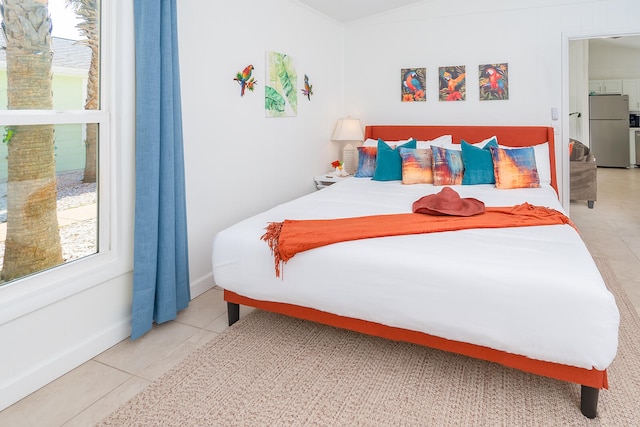 bedroom with tile patterned floors, stainless steel refrigerator, and multiple windows