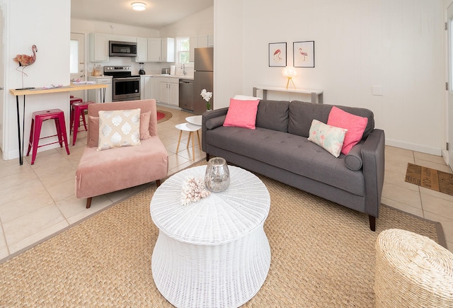 living room featuring sink, light tile patterned floors, and vaulted ceiling