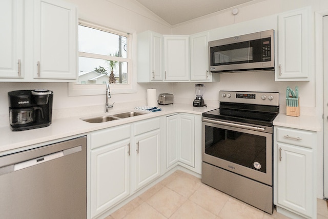 kitchen with sink, white cabinets, lofted ceiling, light tile patterned floors, and appliances with stainless steel finishes