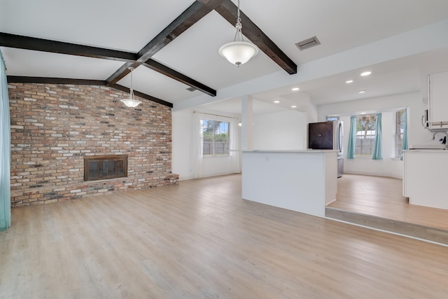 unfurnished living room featuring vaulted ceiling with beams, light hardwood / wood-style flooring, brick wall, and a brick fireplace