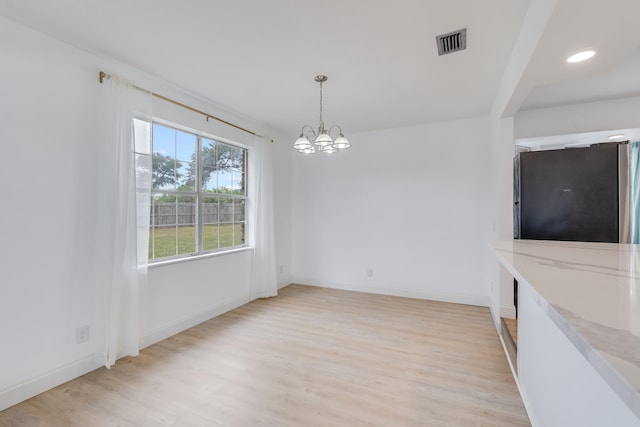 unfurnished dining area with light hardwood / wood-style floors and an inviting chandelier