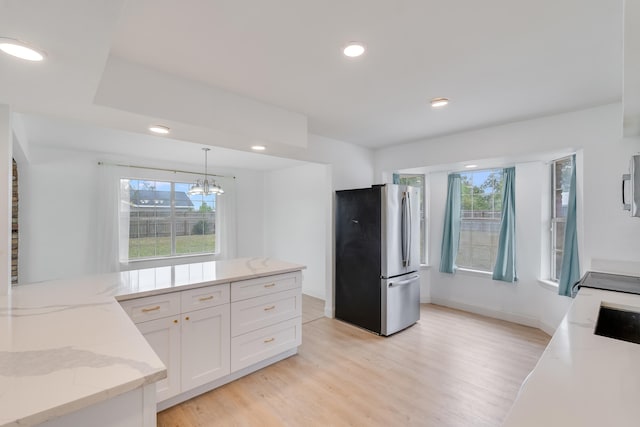 kitchen featuring light stone countertops, appliances with stainless steel finishes, pendant lighting, light hardwood / wood-style floors, and white cabinetry