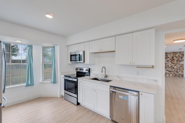 kitchen featuring white cabinets, sink, appliances with stainless steel finishes, and light hardwood / wood-style flooring