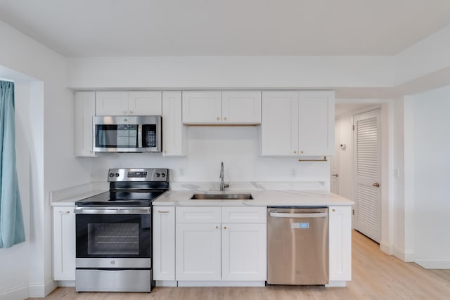 kitchen with sink, white cabinets, stainless steel appliances, and light wood-type flooring