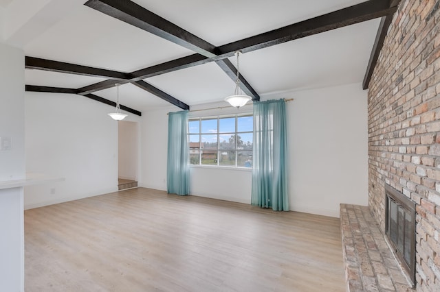 unfurnished living room with beam ceiling, a brick fireplace, and light wood-type flooring