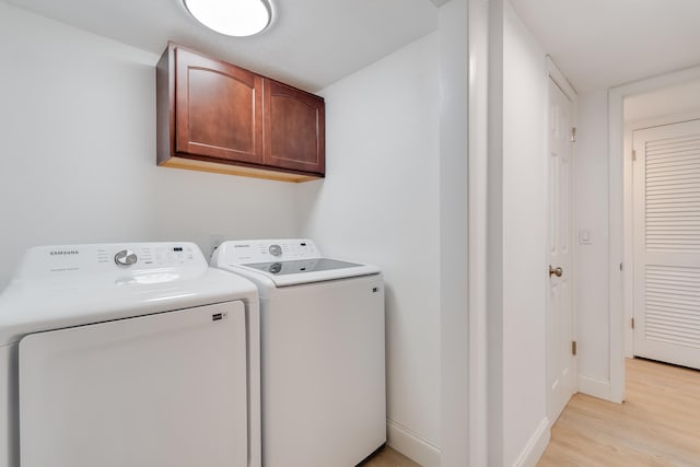 washroom with separate washer and dryer, cabinets, and light hardwood / wood-style floors