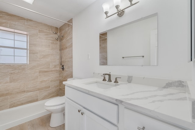 bathroom with vanity, toilet, hardwood / wood-style flooring, and a tile shower